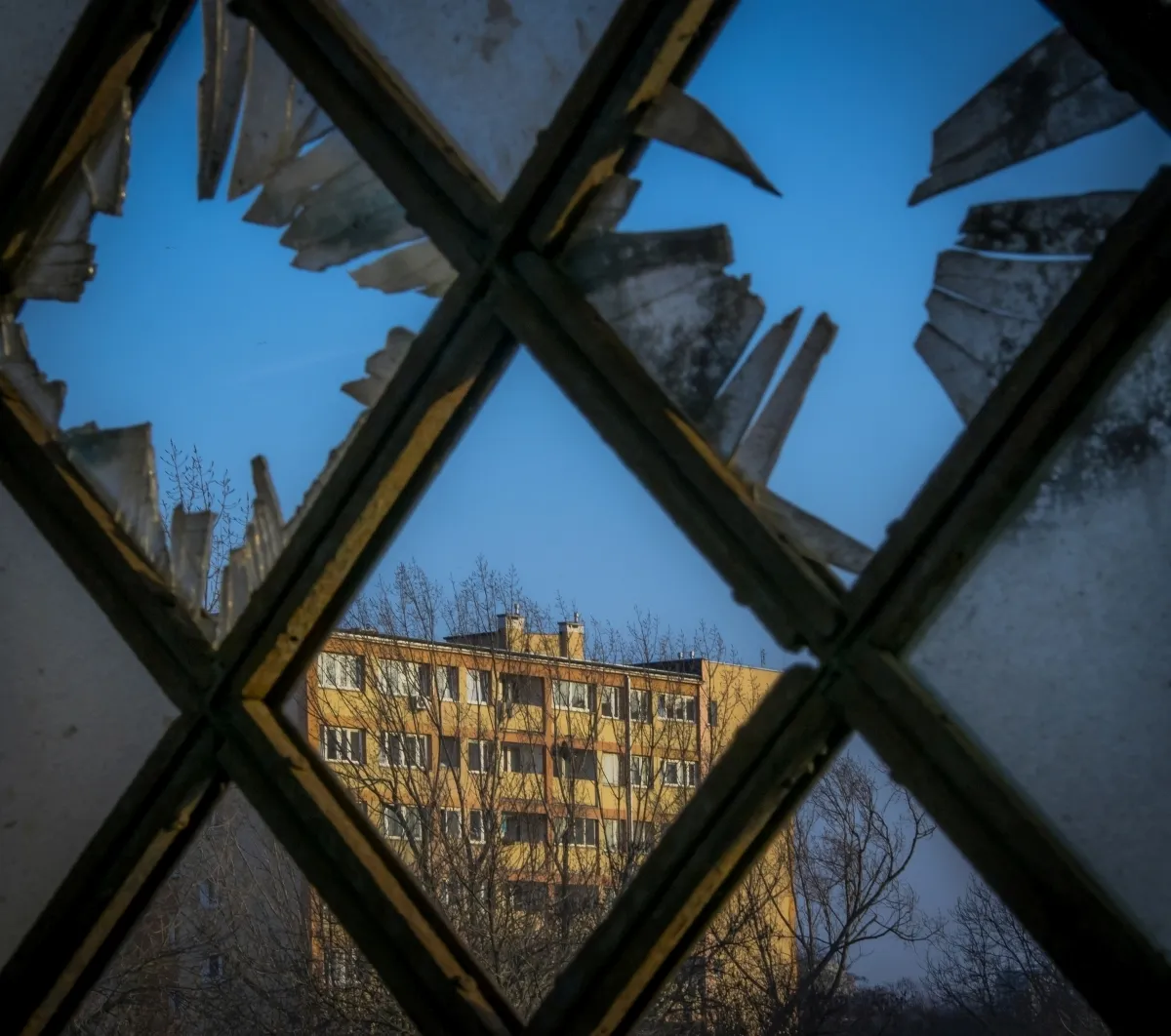 Yellow apartment block reflected in shattered windowpanes